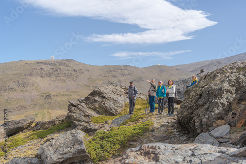 group of hikers with walking sticks in the mountains contemplate the landscape of the Sierra Nevada.