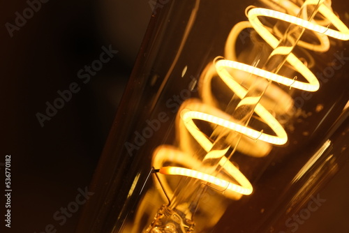 macro of yellow spiral light bulb filament at night. 