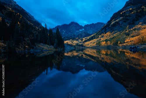 Early morning blue hour at Maroon Bells outside of Aspen Colorado at dawn with cloudy sky and mirrored lake refleciton 