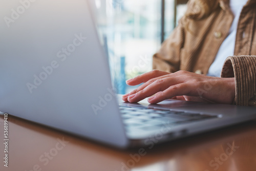 Closeup image of a woman working and touching on laptop computer touchpad