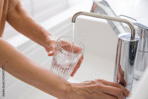 浄水器からコップに水を入れる女性の手元