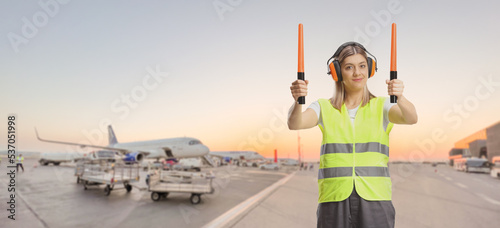 Female aircraft marshaller with wands working on an airport apron