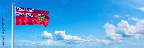 Manitoba - Canada flag waving on a blue sky in beautiful clouds - Horizontal banner 