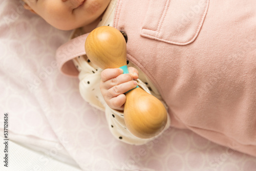 Baby holding a wooden rattle toy