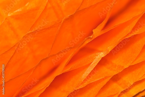 Orange colored ruffled paper cells abstract patterns and textures background with shallow depth of field.