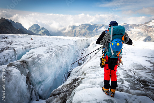 Alpinist standing glacier above crevasse mountains ridge view