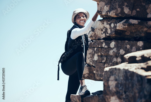 Black woman, climbing a rock mountain and adventure in nature for healthy exercise or sport workout. African American female in sports fitness with smile for summer rocky climb in South Africa
