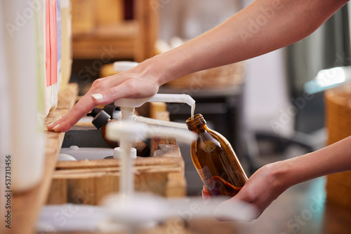 Close Up Of Woman Refilling Glass Bottle With Liquid Soap In Sustainable Zero Waste Plastic Free Store