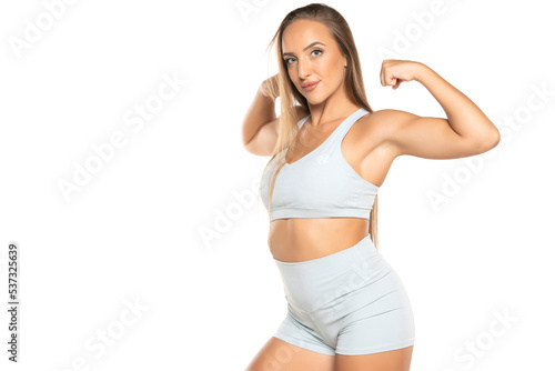 young sports woman with long hair in a shorts and top showing biceps on a white background