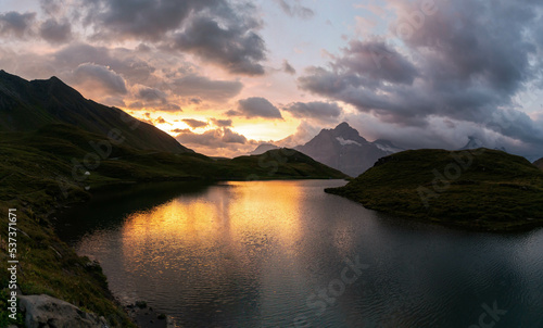 Colorful summer sunrise on Bachalpsee lake with Schreckhorn and Wetterhorn peaks on background. Picturesque morning scene in the Swiss Bernese Alps, Switzerland, Europe.