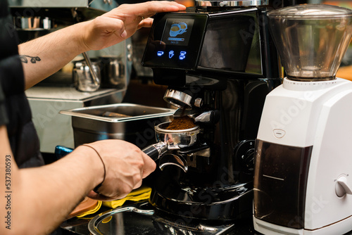 Hands of a barista making coffee in an espresso machine.