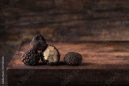 Black truffles in antique wooden board, rustic style, low key, selective focus, macro, copy space for text. Season of black truffle. Autumn gourmet cuisine of Piedmont, Italy, Spain and France