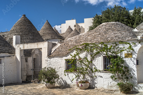 narrow cobblestone streets and round stone trulli houses in Arbelobello. Stone pointed roofs and brick stone whitewashed houses on a sunny day
