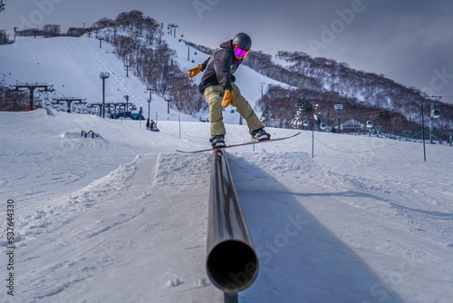 Snowboarder doing a boardslide in a rail at the snowpark