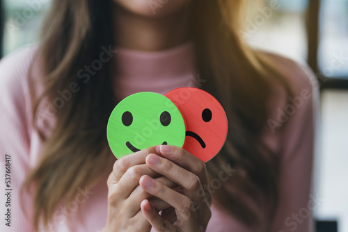 Woman Hands holding sad face hiding or behind happy smiley face, bipolar and depression, mental health concept, personality, mood change, therapy healing split concept.