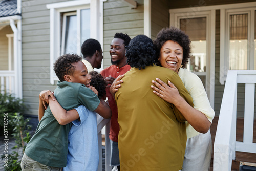 Big African American family embracing outdoors welcoming guests for party