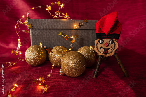 Popping log or traditional catalan "Caga tió" surrounded by Christmas balls and lights. Christmas decoration
