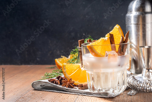 Autumn alcohol drink, boozy refreshing milk and honey cocktail with benedictine orange and cinnamon spice, wooden kitchen table background copy space