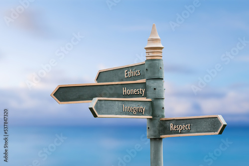ethics honesty integrity respect four word quote written on fancy steel signpost outdoors by the sea. Soft Blue ocean bokeh background.