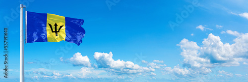 Barbados flag waving on a blue sky in beautiful clouds - Horizontal banner