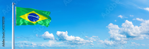 Brazil flag waving on a blue sky in beautiful clouds - Horizontal banner