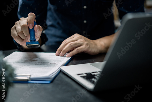 Man stamping approval of work finance banking or investment marketing documents on desk.