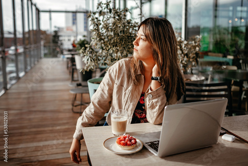 Young mexican woman is enjoying her morning coffee on the terrace of modern cafe before working day. Morning routine, mental health, wellness and slow living