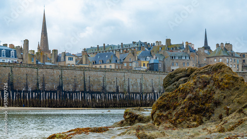 The traditional ancient skyline of Saint Malo, Brittany, France, with its famous bastions around the historical centre. Big rock in the foreground.