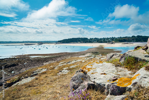 The coastline of Brittany, France from the famous "Ilot Saint Michel" (Saint Michel Island), during low tide. On the background the vast beach with sands and blue sky.