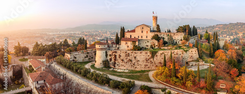 Panoramic drone view on medieval fortress Castello di Brescia, via del Castello and historical building complex on Cidneon mountain slope at autumn. Brescia, Lombardy, Northern Italy