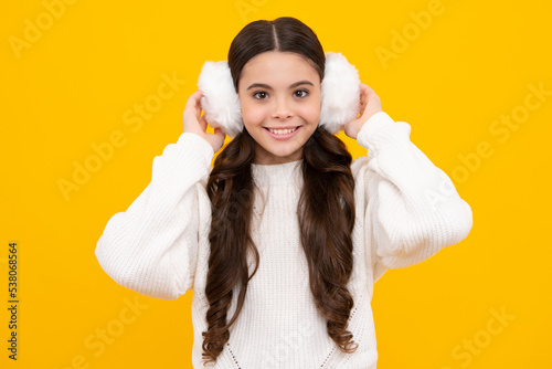 Fashion happy young woman in winter warm earmuff ear-flaps and sweater having fun over colorful blue background. Happy face, positive and smiling emotions of teenager girl.