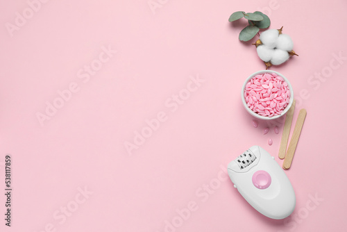 Modern epilator, depilatory wax and fluffy cotton flower on pink background, flat lay. Space for text