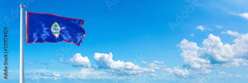 Guam flag waving on a blue sky in beautiful clouds - Horizontal banner