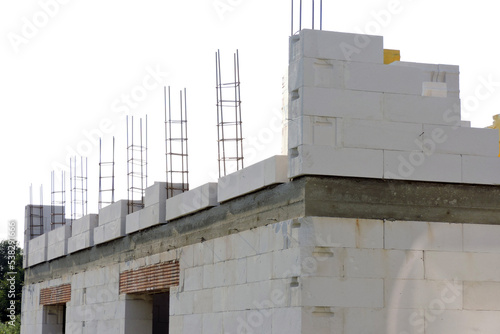 A reinforced concrete beam, steel reinforcement for pillars on the first floor of a house under construction, a reinforced brick lintel, a rough window opening , walls made of aac