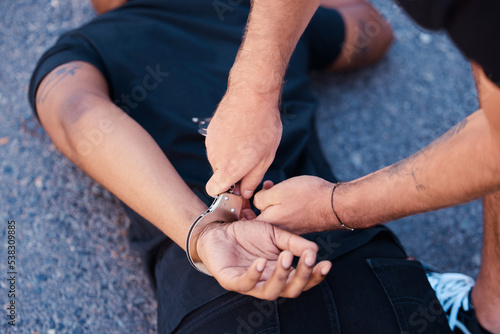 Hands, handcuffs and man on floor with police agent, justice and human rights in Iran to stop protest. Crime, law and freedom in arrest in street, criminal or thief arrested in city by police officer