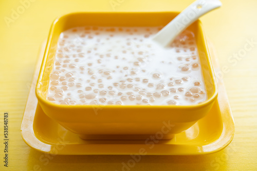 angle view bowl of Chinese syrup of sago with coconut juice on yellow background