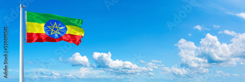 Ethiopia flag waving on a blue sky in beautiful clouds - Horizontal banner
