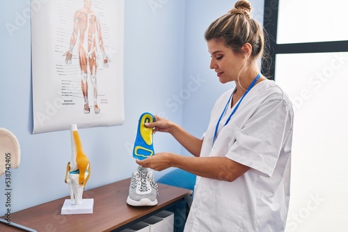 Young blonde woman podiatrist holding insole at clinic