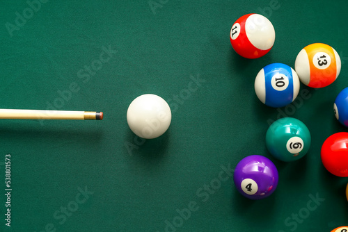 Colorful billiard balls with cue on table