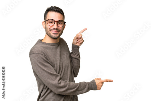 Young handsome caucasian man over isolated background pointing finger to the side and presenting a product