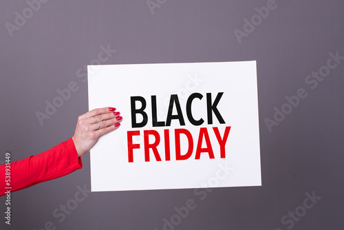 Female hand holding a black friday poster. Studio shot. Commercial concept.