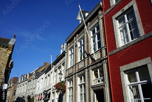 Häuserzeile mit restaurierten Altbauten in der Stokstraat vor blauem Himmel im Sonnenschein in der Altstadt von Maastricht an der Maas in der Provinz Limburg der Niederlande