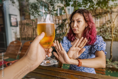 Funny sober woman refuses an extra glass of beer at the pub. Say no and stop to addiction and excessive alcohol consumption.