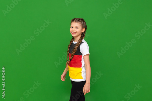 A child with a German flag on a T-shirt. Educational German language courses for schoolchildren. Green isolated background.