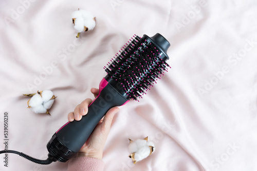 Electric blowout brush hair dryer on a pink background