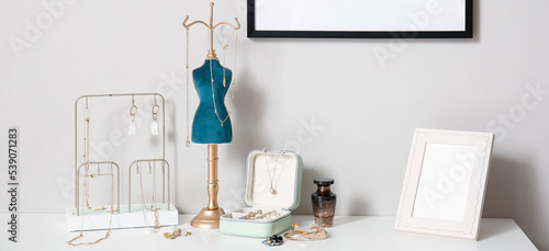 Different stands and box with stylish jewelry on table near light wall