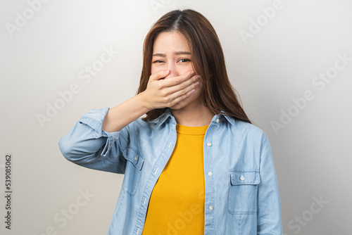 Portrait of pretty brunette hair, disgust smell bad breath strong asian young woman, girl covering, close her mouth with hand, expression face disgusting, dislike odor. Isolated on white background.