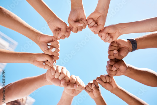 Fist hands, circle and community support diversity people, protest group and freedom fight on blue sky background. Below solidarity, teamwork and motivation for justice goal, trust and society power