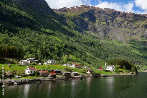 Bakka village with small houses in Norway next to a lake with trees and a river in the background