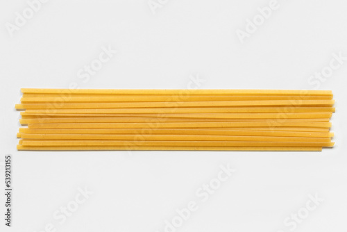 Uncooked durum fettuccine pasta isolated on white background. Raw spaghetti or noodles